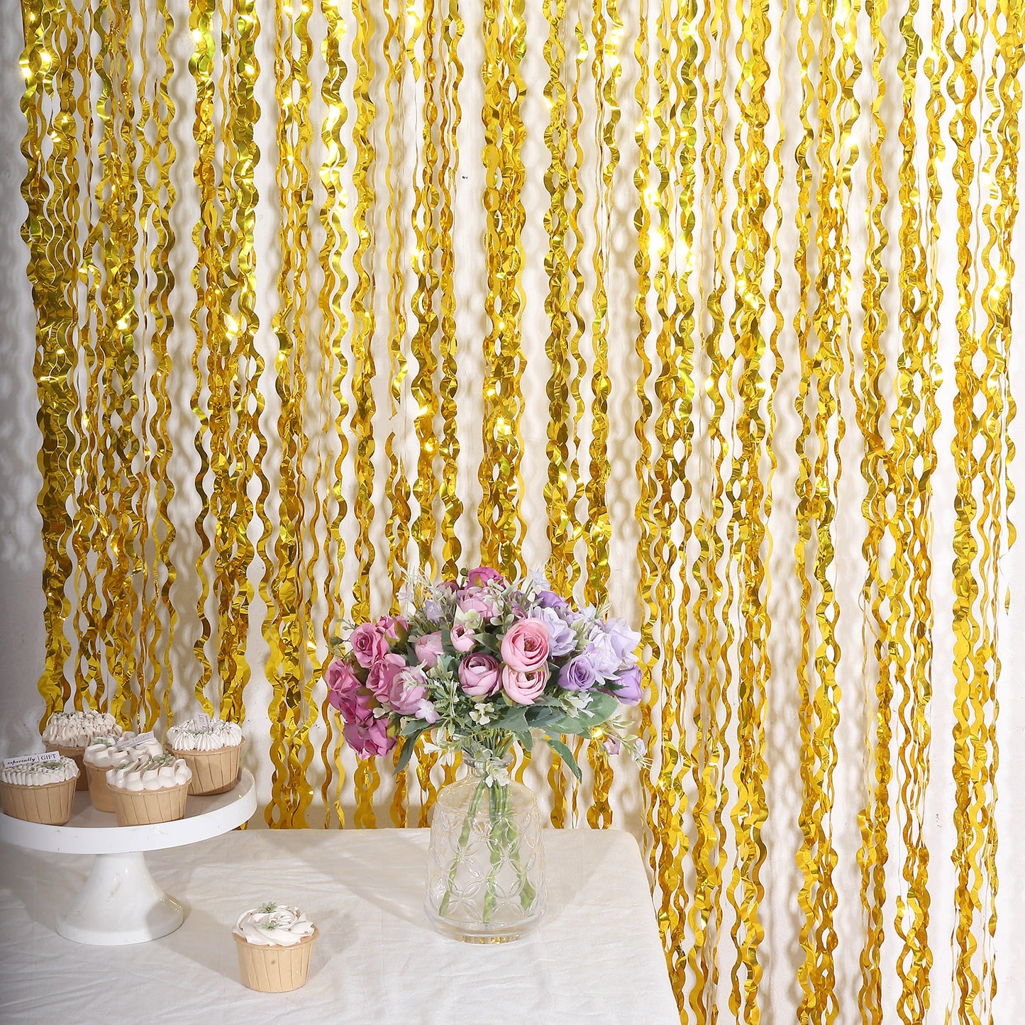 Metallic gold wavy foil fringe backdrop with curly tinsel streamers.