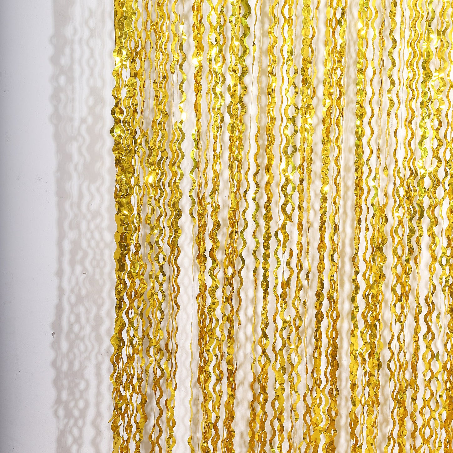 Metallic gold wavy foil fringe backdrop curtain for parties and photo booths.