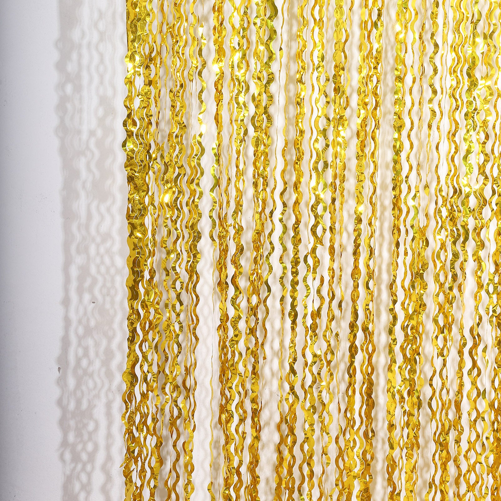 Metallic gold wavy foil fringe backdrop curtain for parties and photo booths.