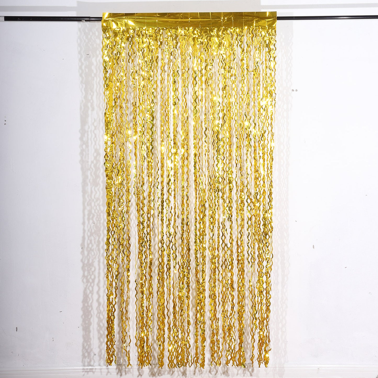 Metallic gold wavy foil fringe backdrop curtain for parties and photo booths.
