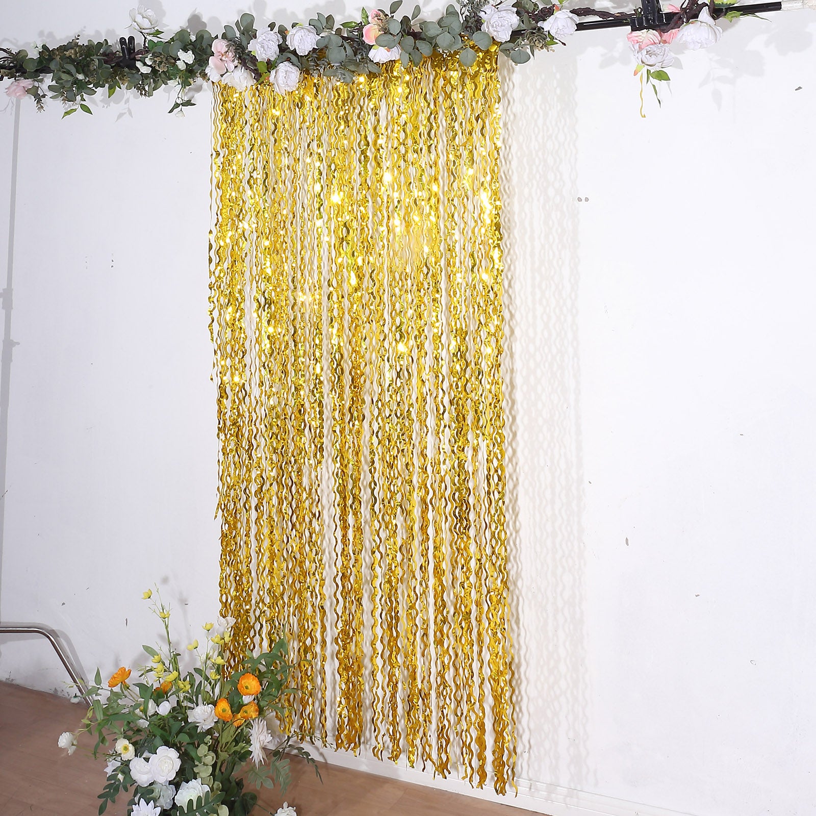 Metallic gold wavy foil fringe party backdrop curtain for photo booths.