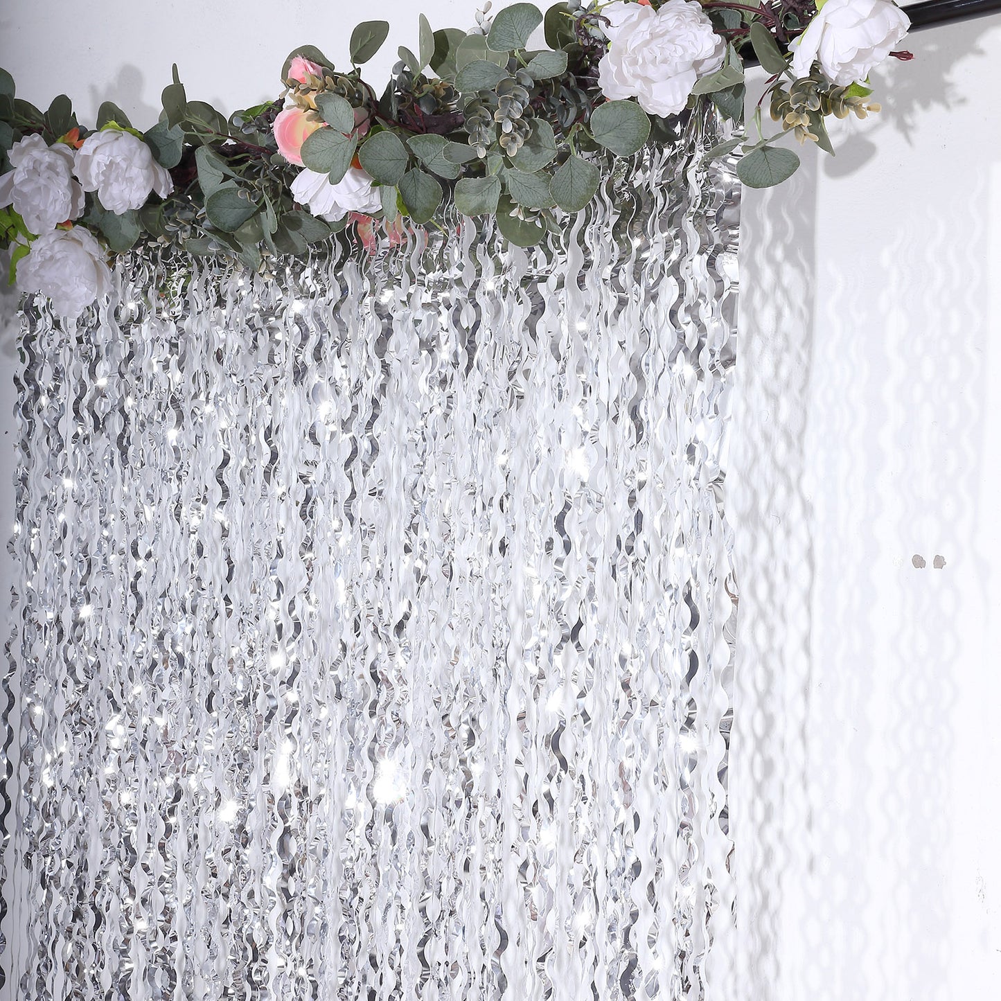 Metallic silver wavy foil fringe backdrop with curly tinsel streamers.
