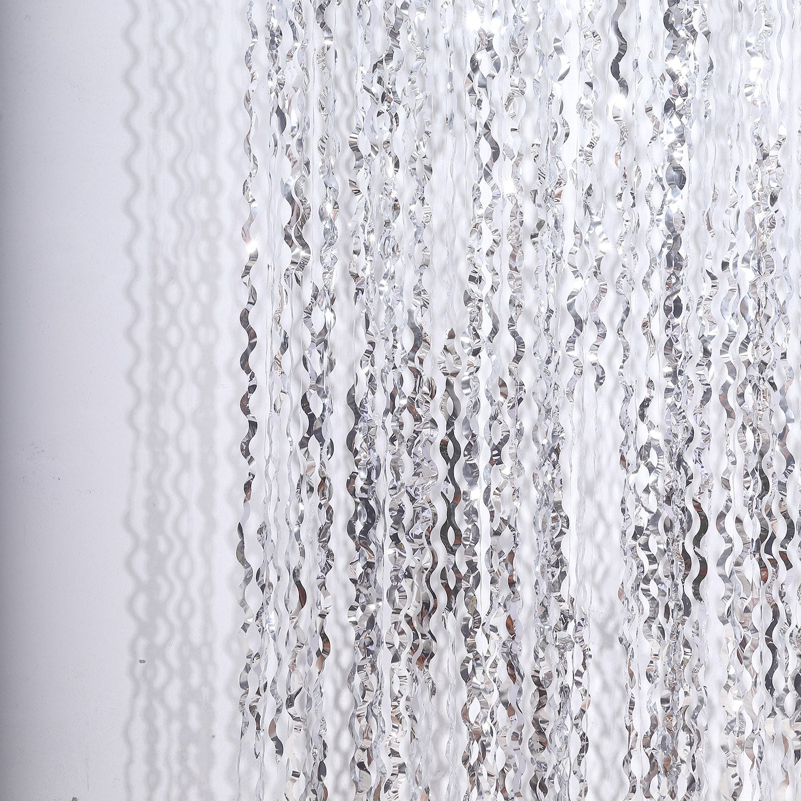 Metallic silver wavy foil fringe backdrop curtain for parties.