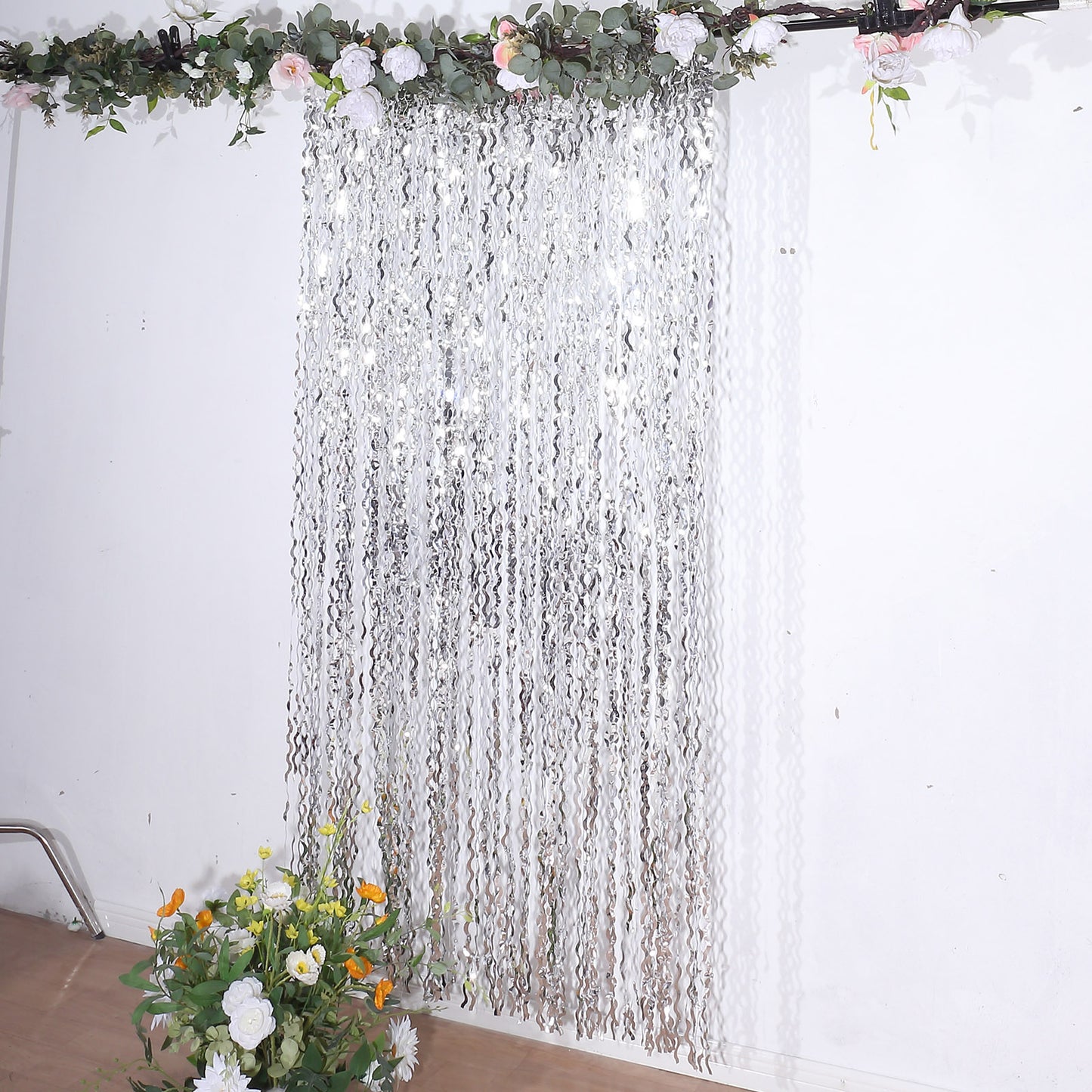 Metallic silver wavy foil fringe backdrop with curly tinsel streamers.