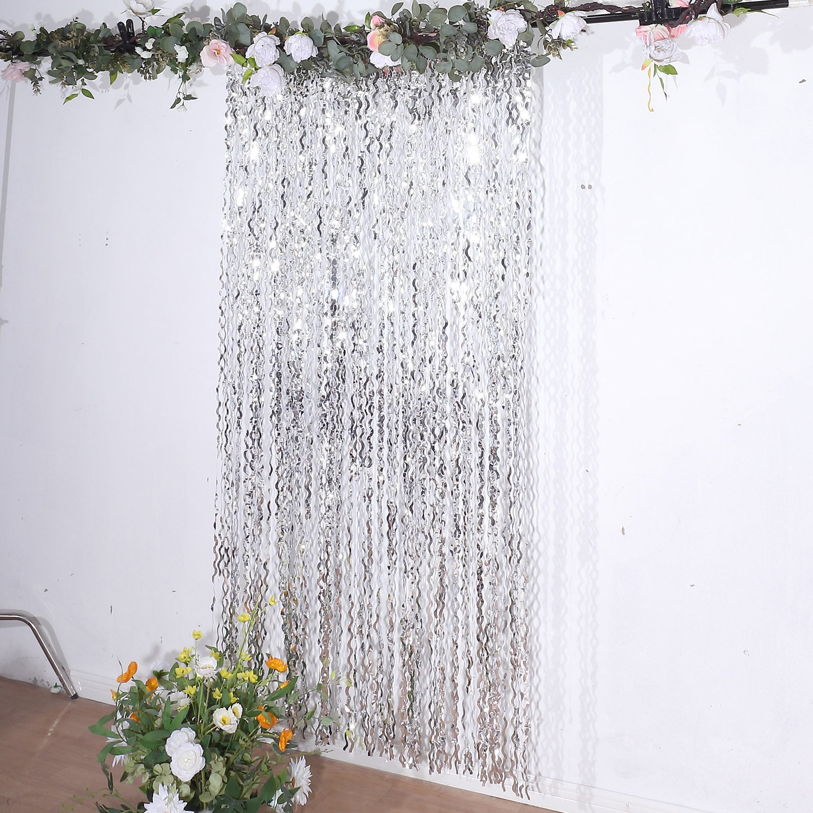 Metallic silver wavy foil fringe backdrop with curly tinsel streamers.