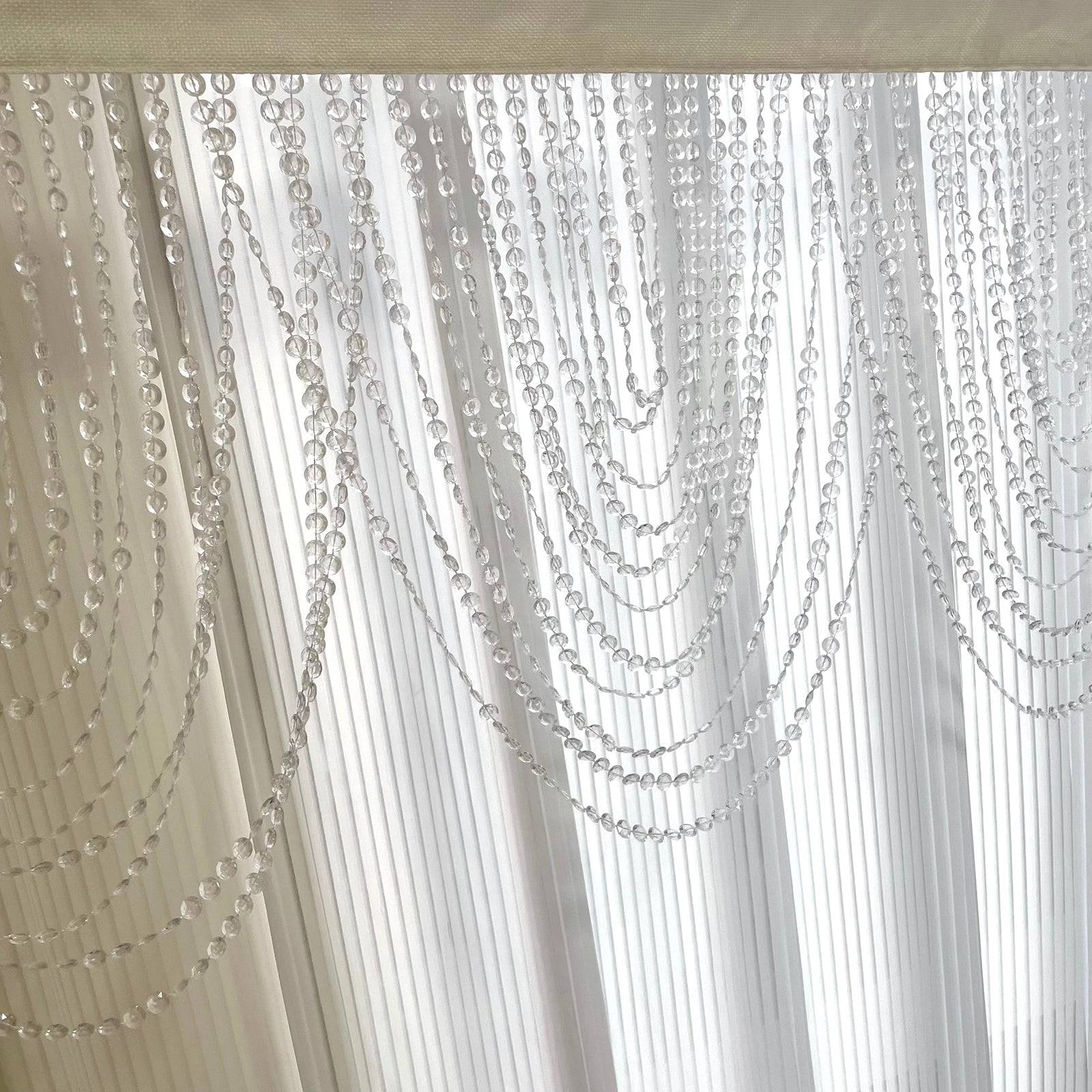 Clear acrylic crystal beaded curtain valance with triple swag design.