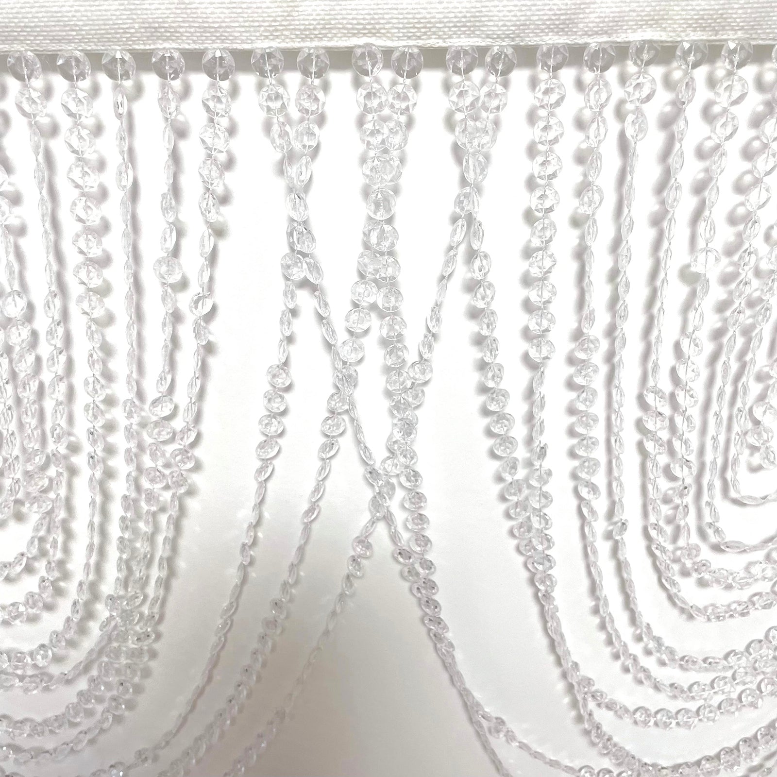 Clear acrylic crystal beaded curtain valance with triple swag design.