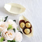 Natural biodegradable wooden boat-shaped food plates with gold-wrapped snacks.
