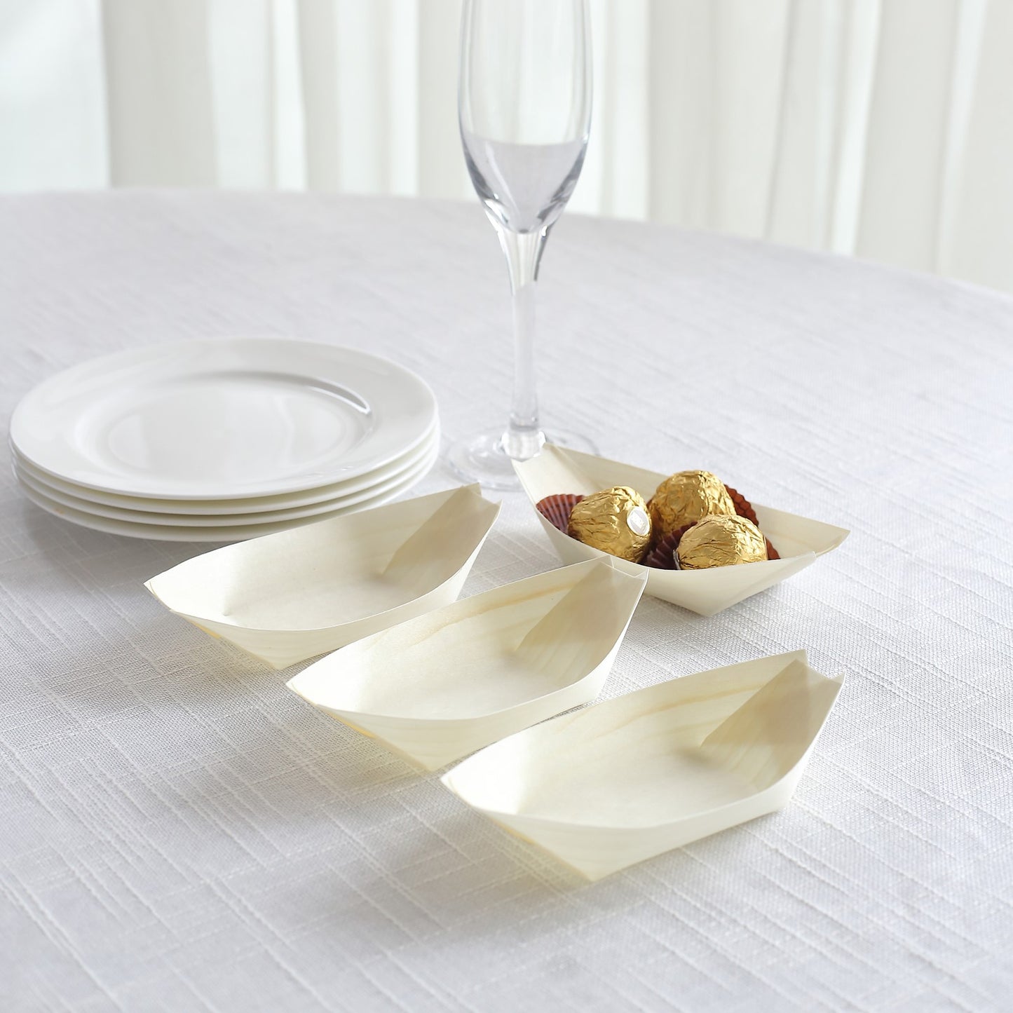 Natural biodegradable wooden boat-shaped food plates on a table.