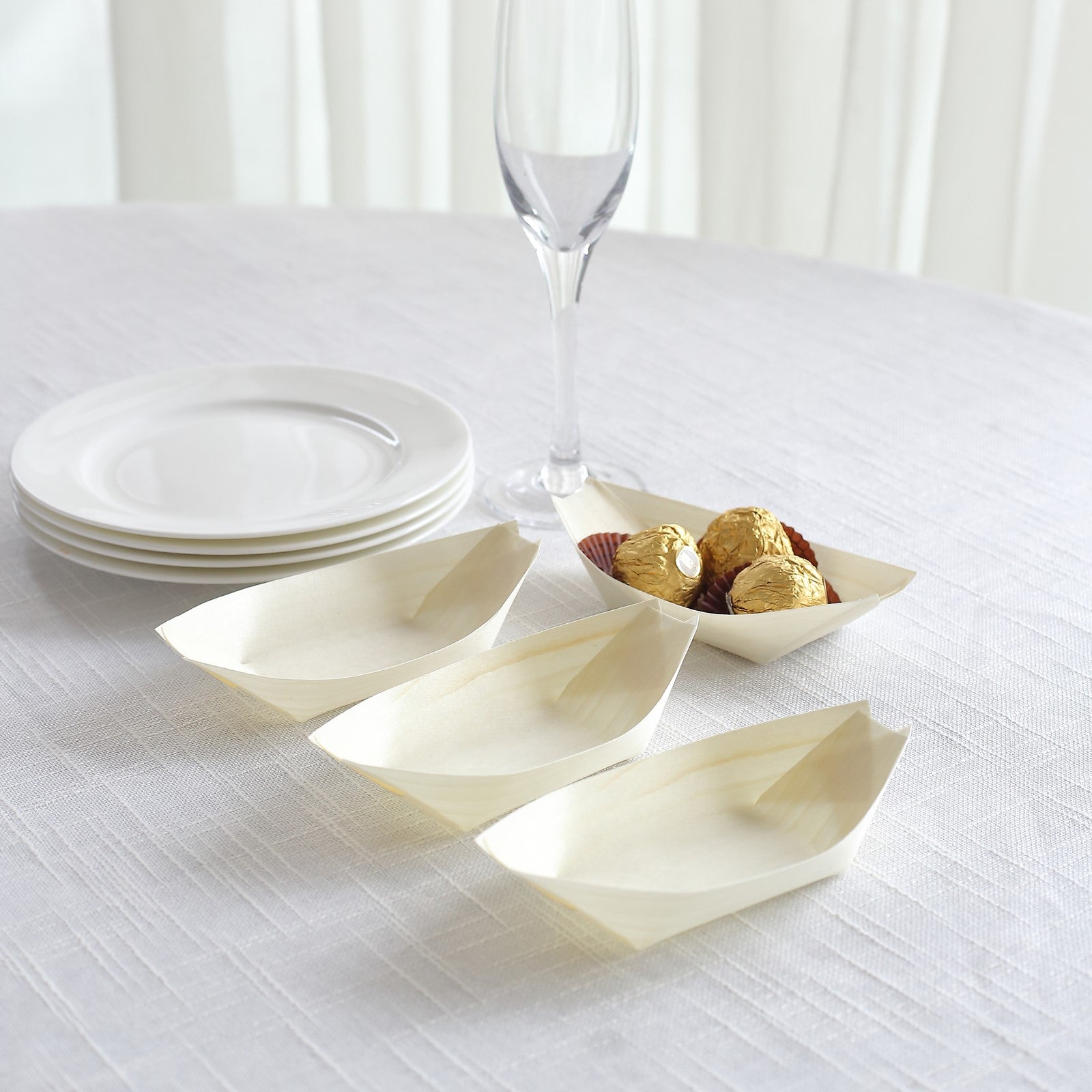 Natural biodegradable wooden boat-shaped food plates on a table.