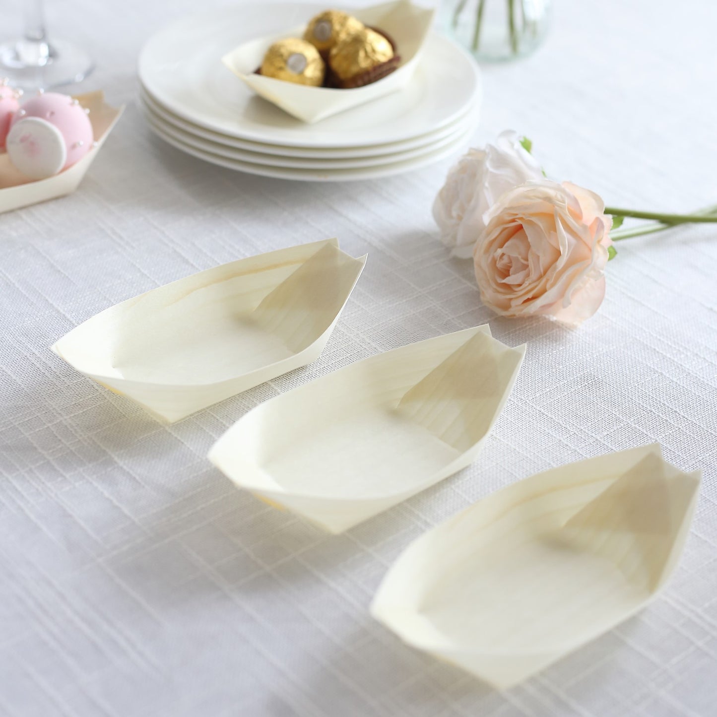 Natural biodegradable wooden boat-shaped plates on a table.
