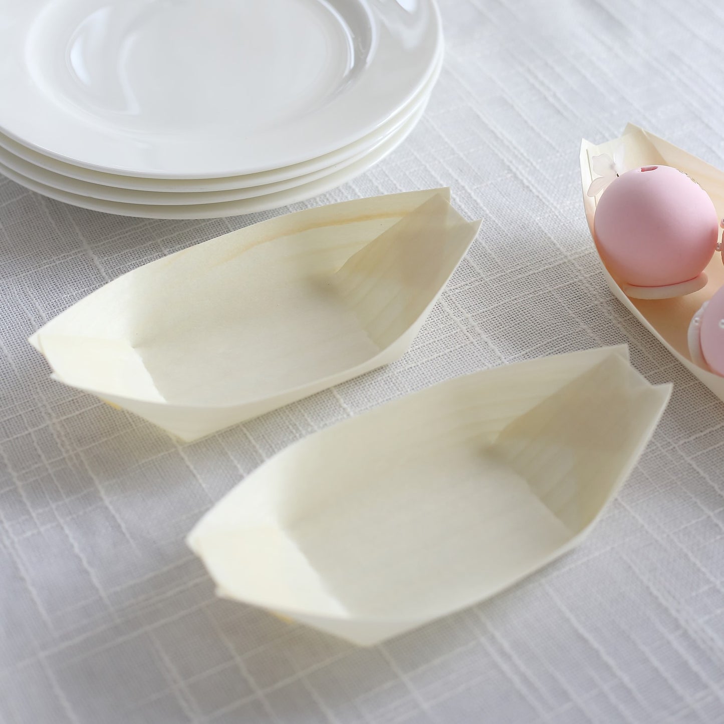 Natural biodegradable wooden boat-shaped food plates in a light beige color.