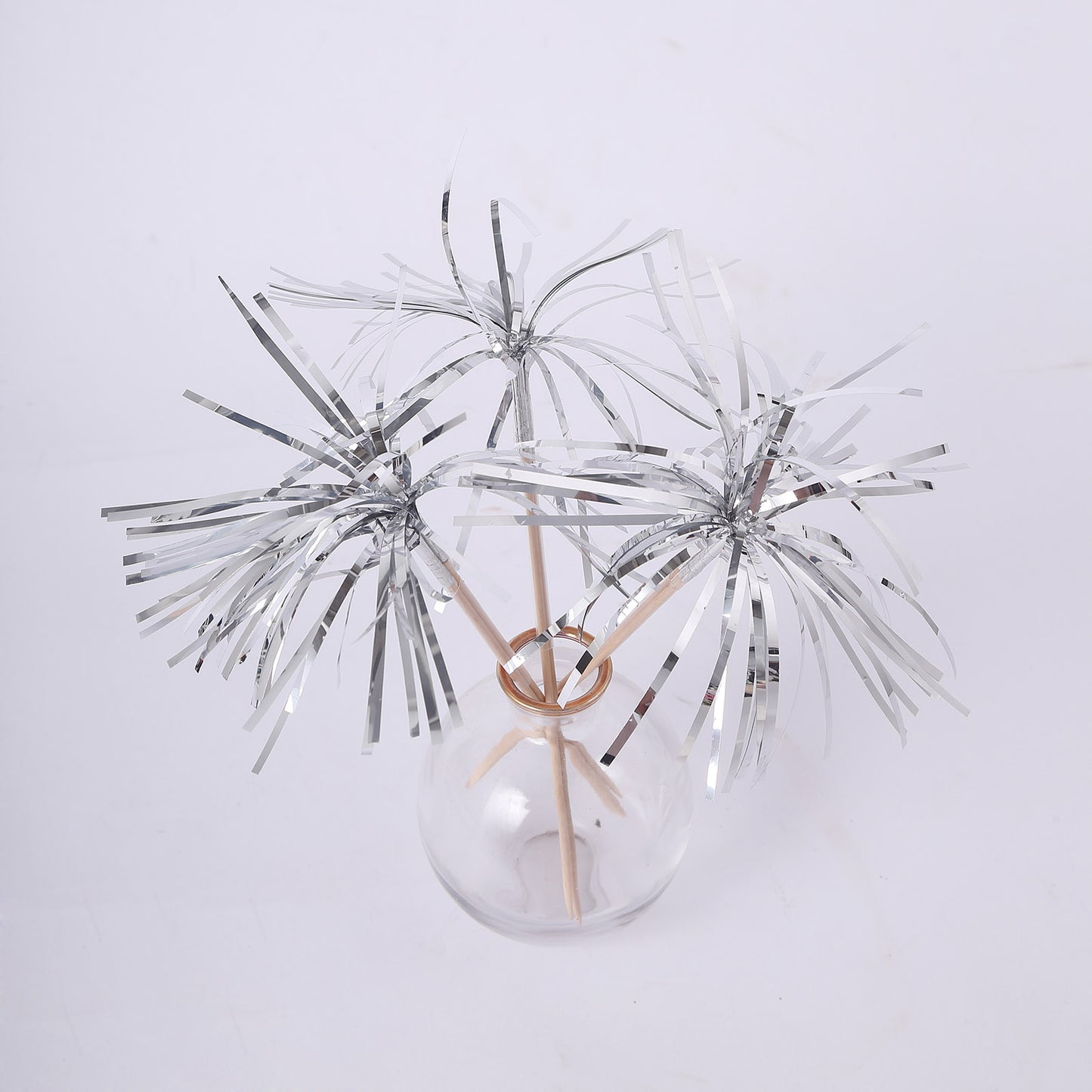Silver firework frills cake toppers in a glass vase.
