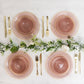 Transparent dusty rose bowls with gold rim on a marble table setting.