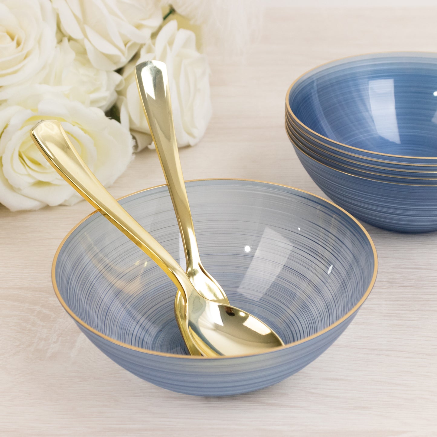 Transparent dusty blue bowl with gold rim and elegant swirl design.