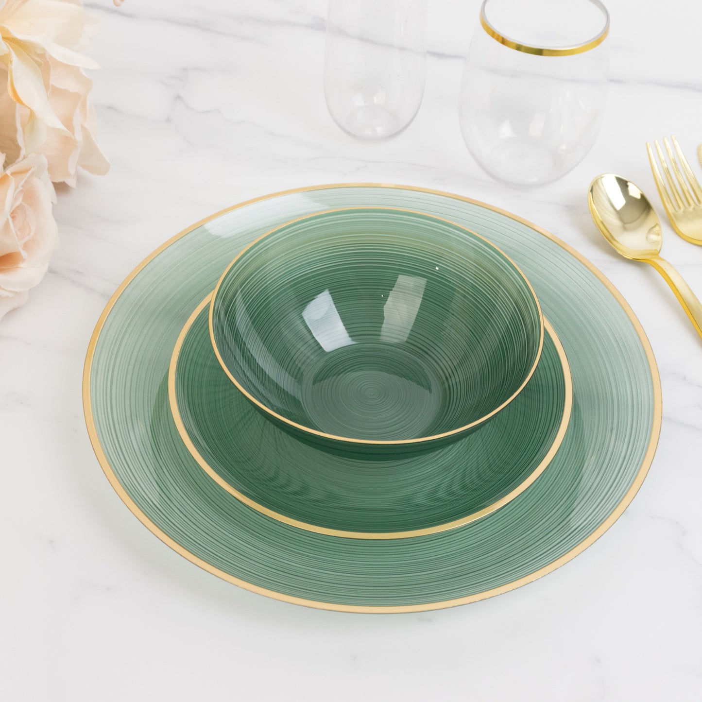 Transparent dusty sage green bowl with gold rim on a marble surface.