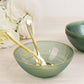 Transparent dusty sage green bowl with gold rim and elegant swirl design.