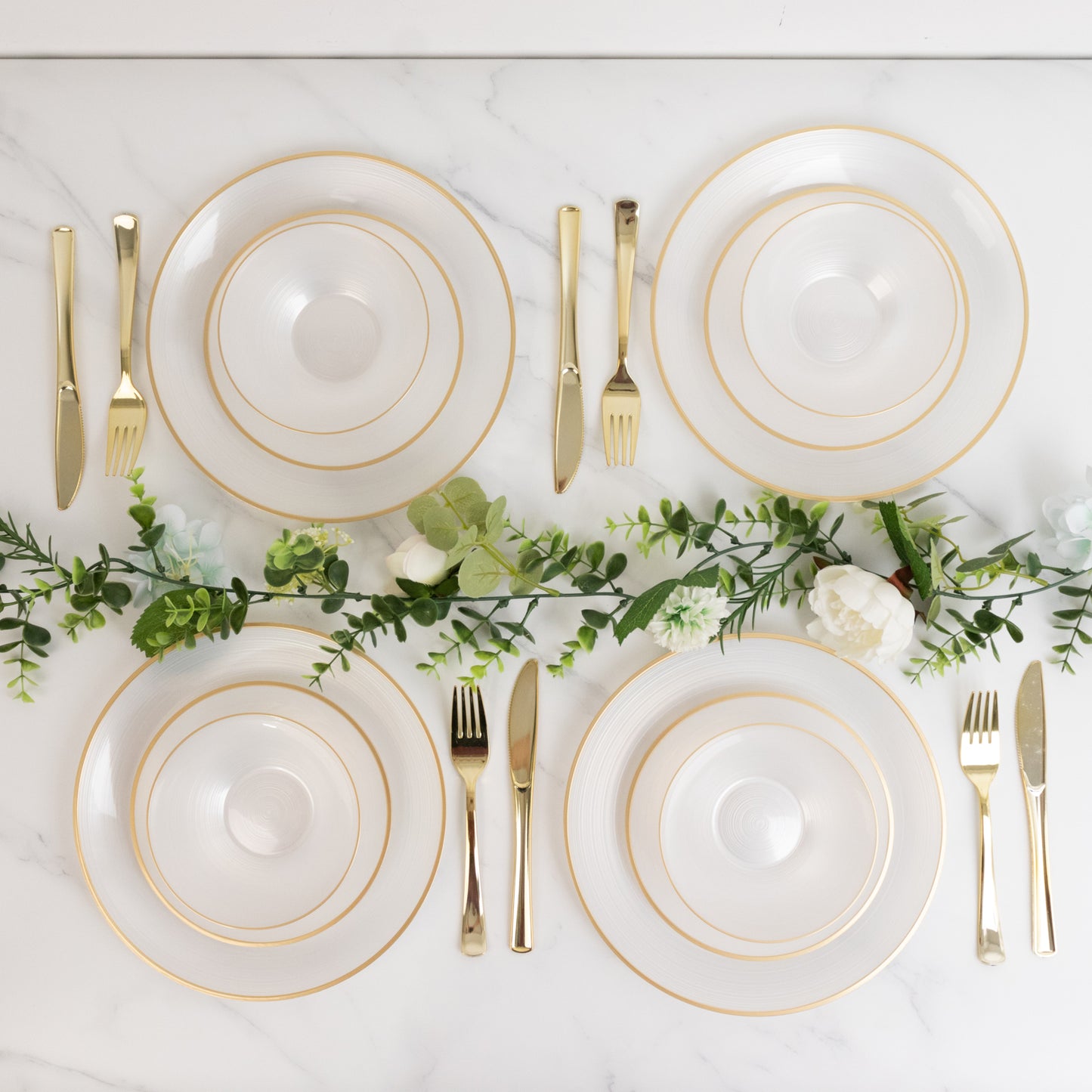 Transparent pearl white bowls with gold rim on a marble surface.