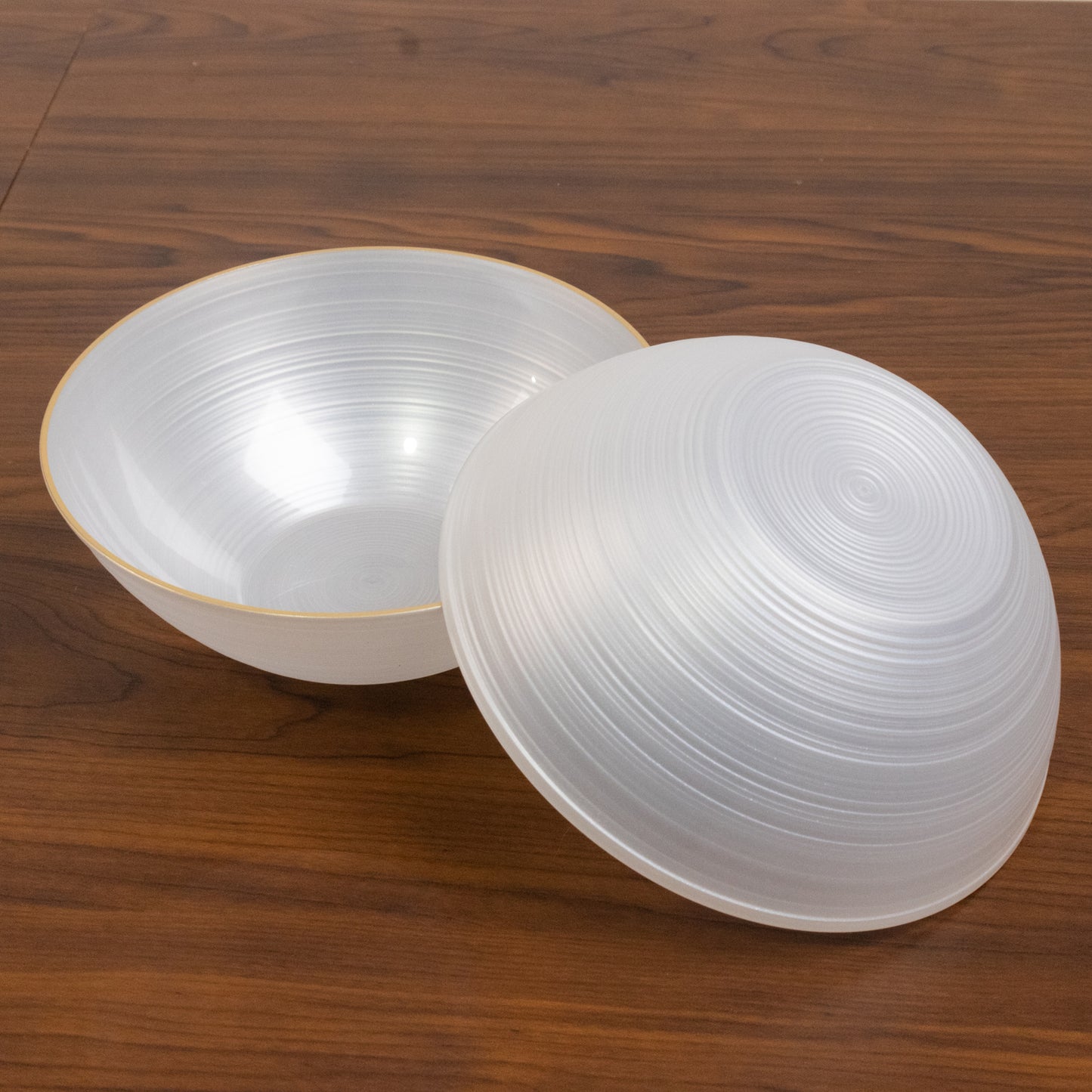 Transparent pearl white disposable bowls with gold rim, elegant swirl design.