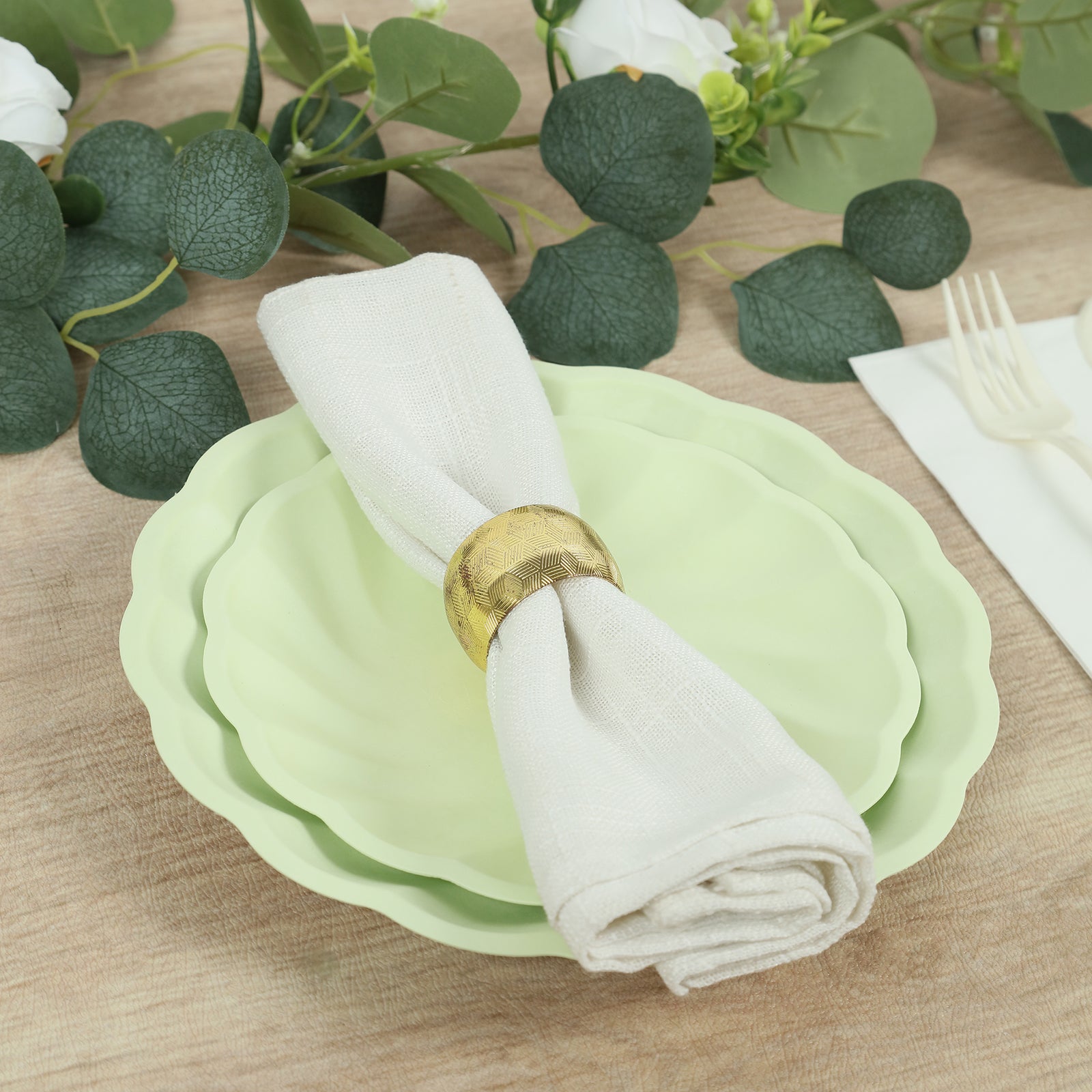 Sage green biodegradable salad plates with a cream napkin and gold ring.
