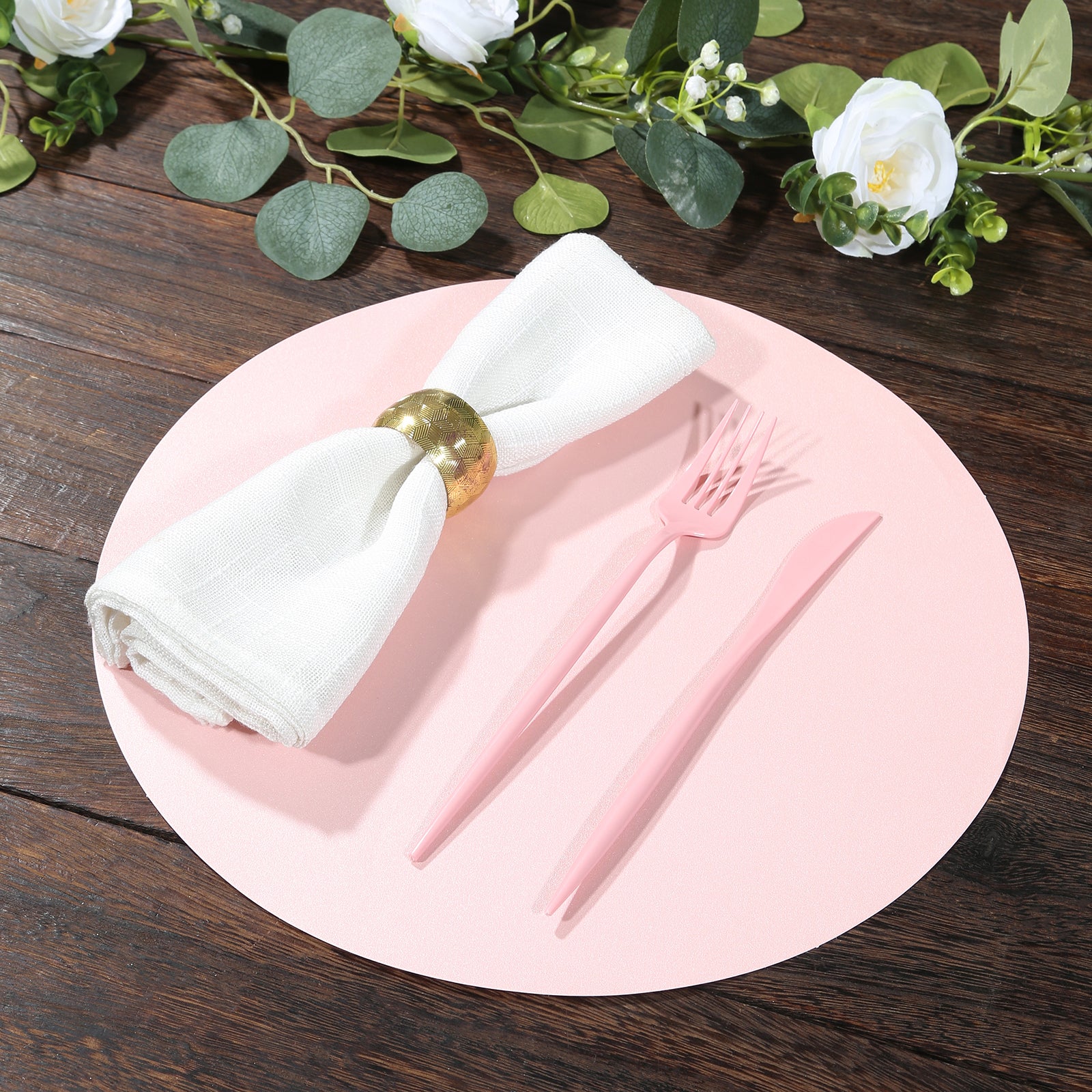 Pink round disposable paper placemat with utensils and napkin.