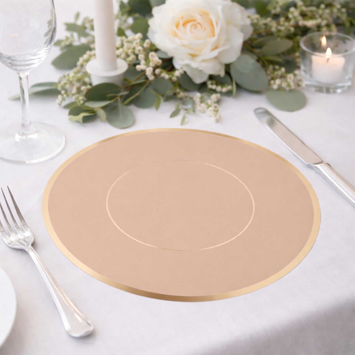 Dusty rose round disposable table placemat with gold rim on a dining table.