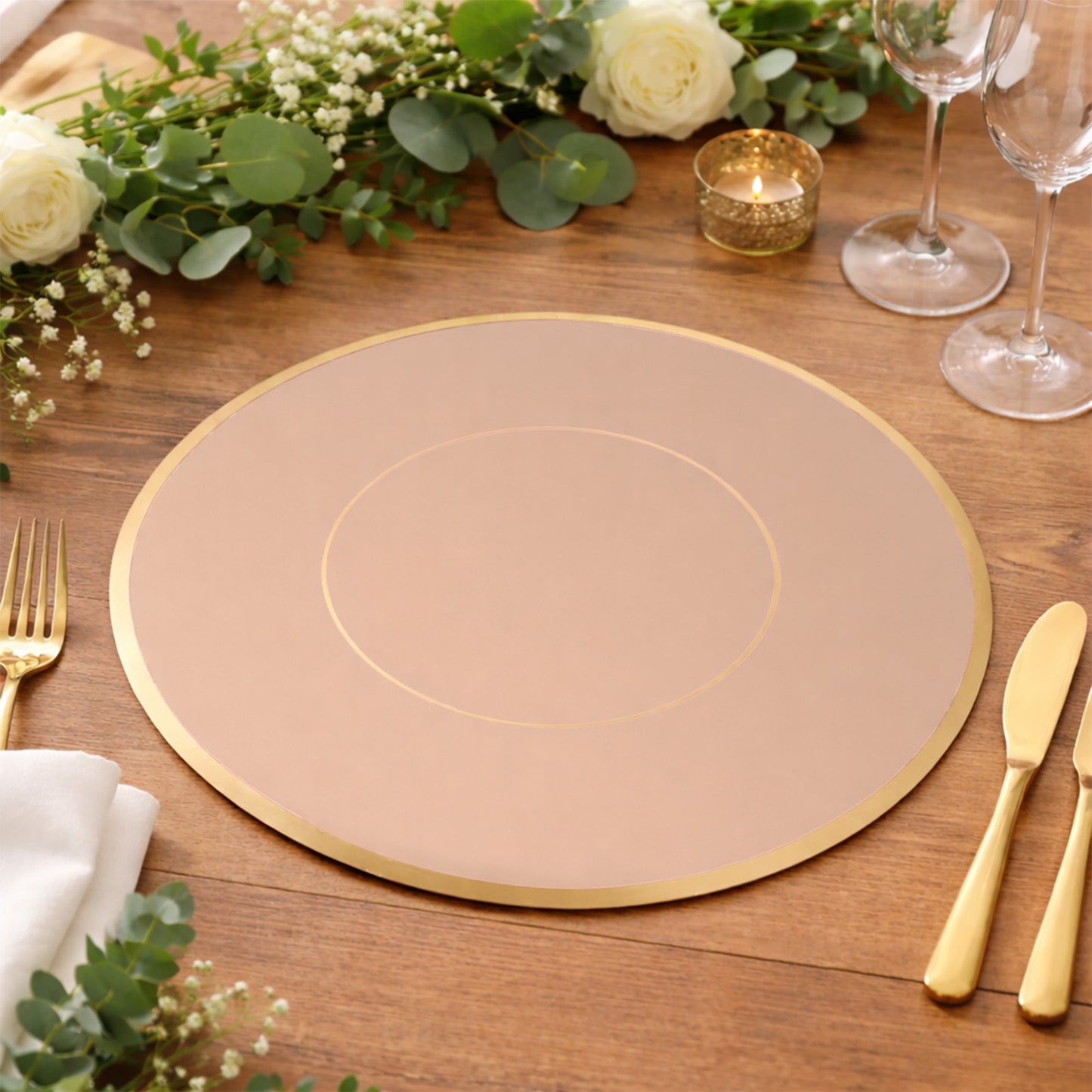 Dusty rose round disposable placemat with gold rim on a wooden table setting.