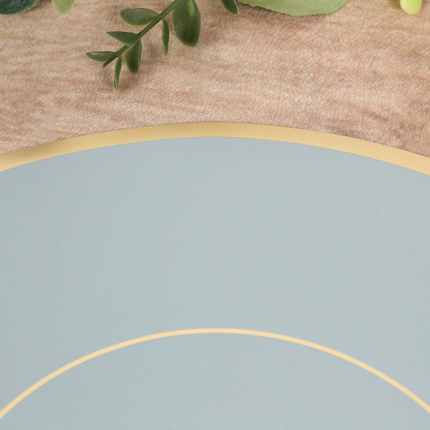 Dusty blue round disposable placemat with gold rim.