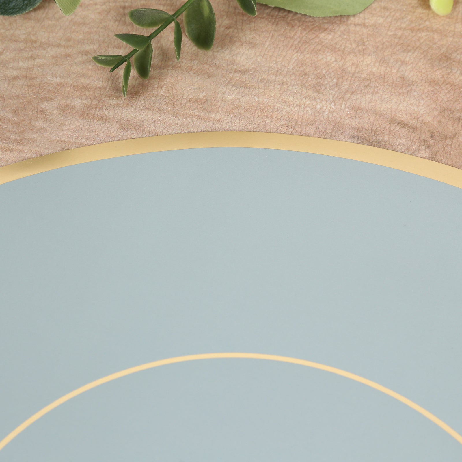 Dusty blue round disposable placemat with gold rim.