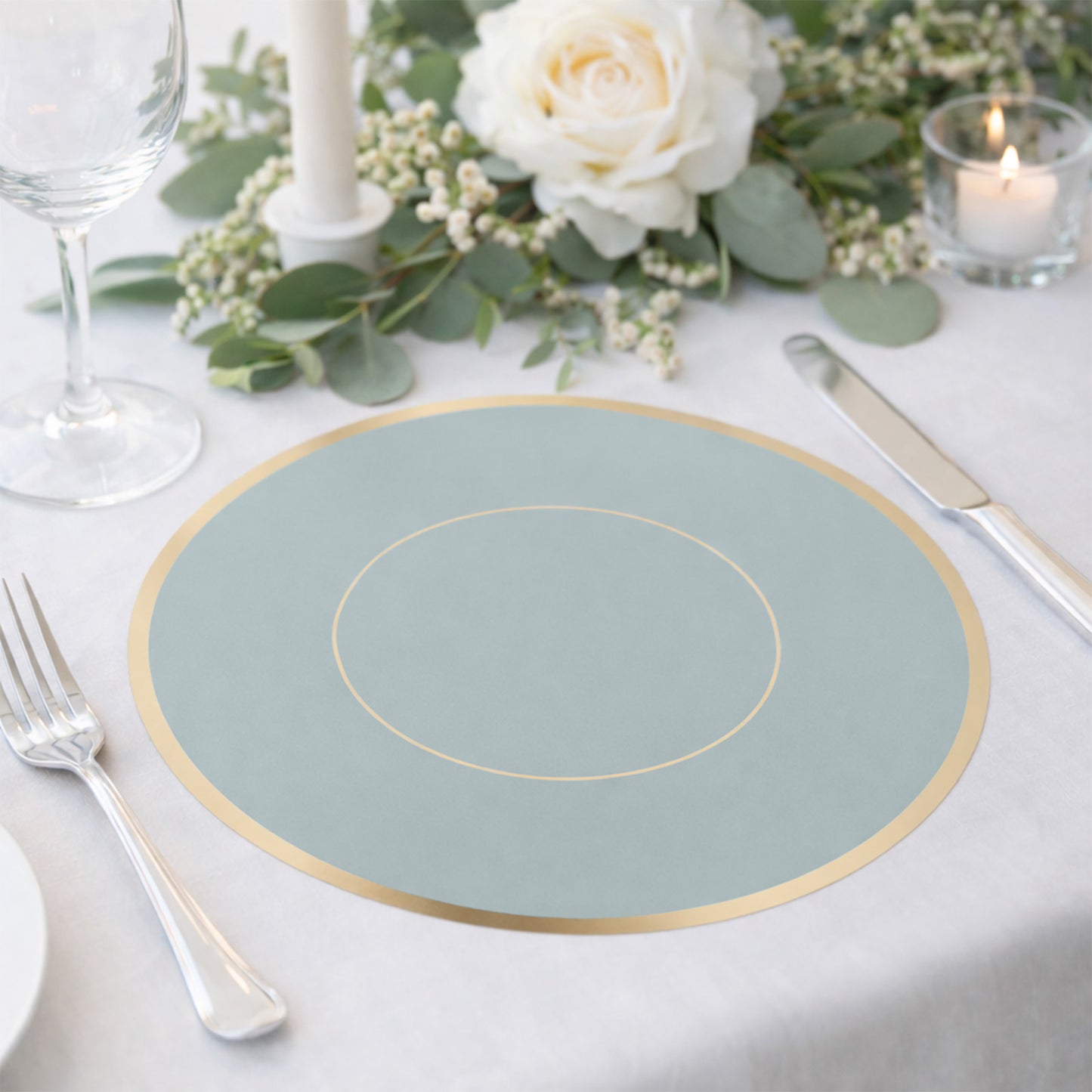 Dusty blue round disposable table placemat with gold rim on a dining table.