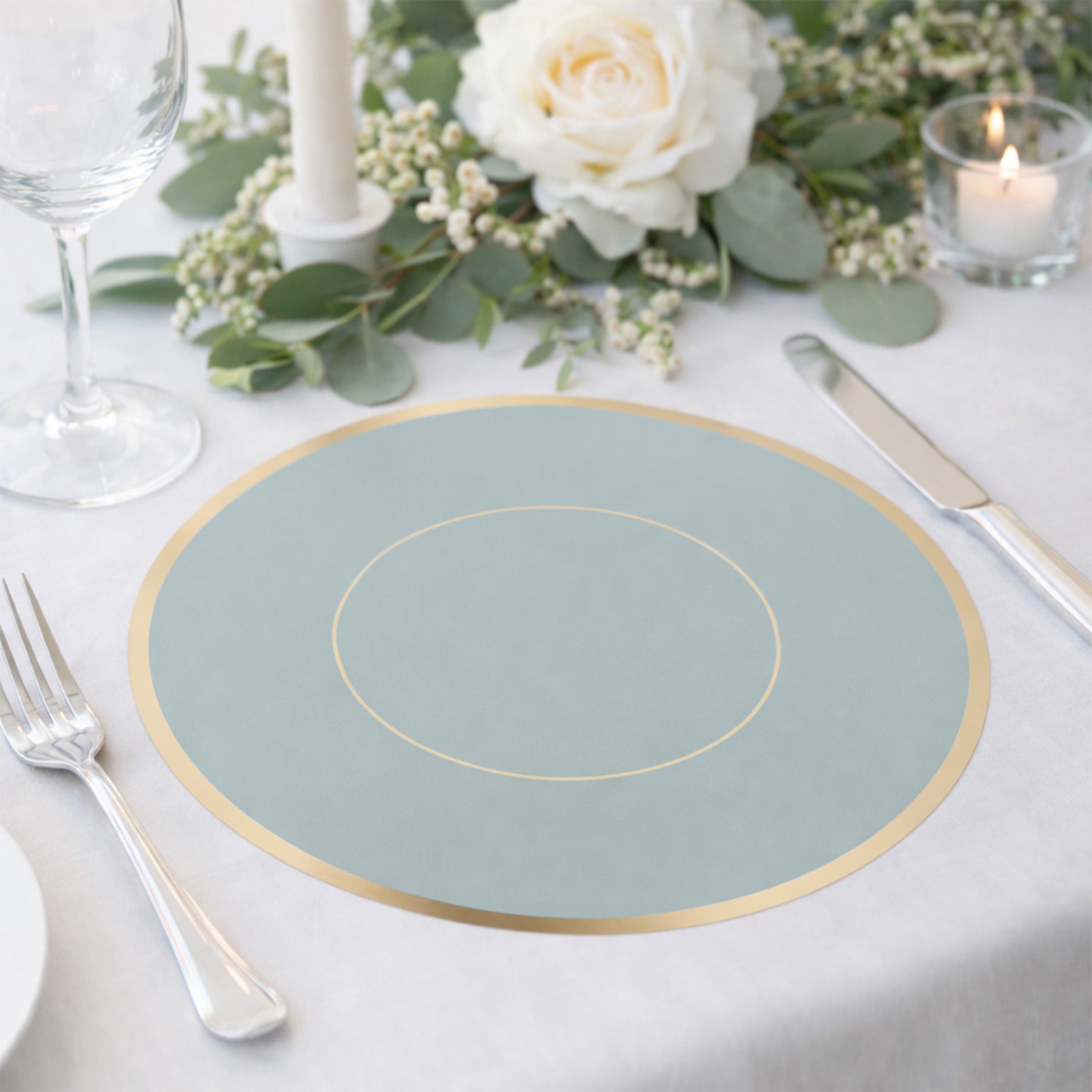 Dusty blue round disposable table placemat with gold rim on a dining table.