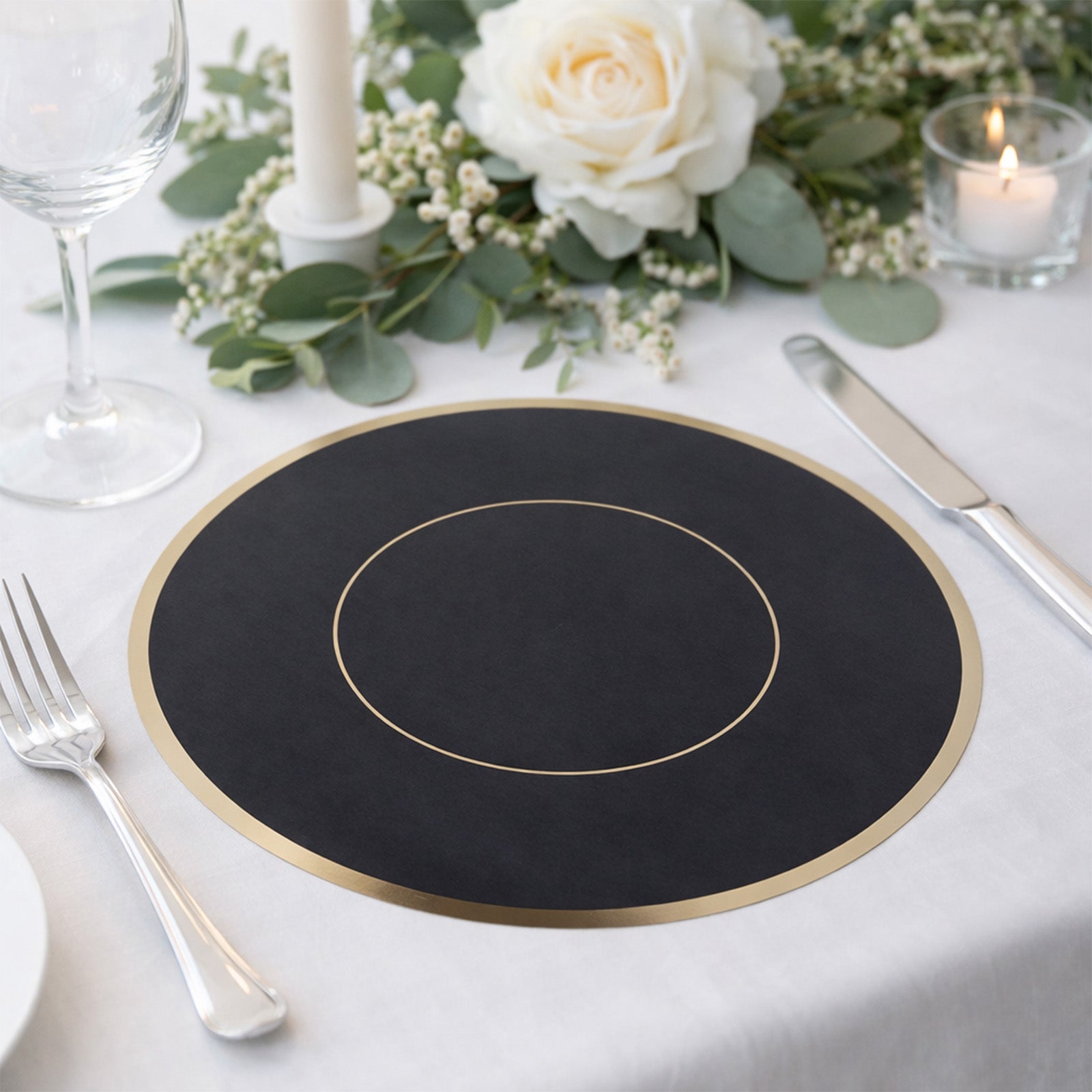Black round disposable placemat with gold rim on a dining table setting.
