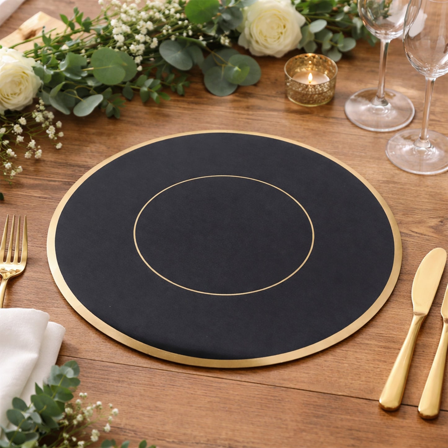 Black round disposable table placemat with gold rim on a wooden table.