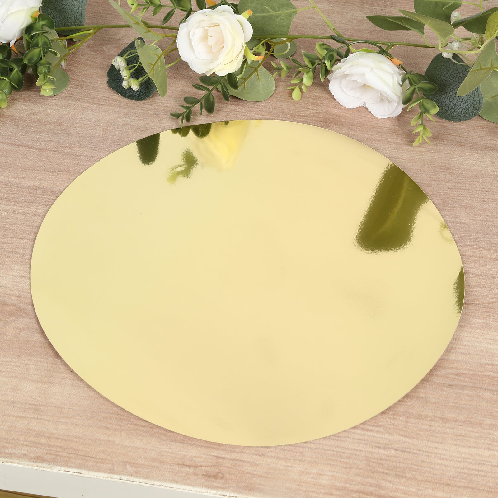 Gold round disposable table placemat on a wooden surface with flowers.
