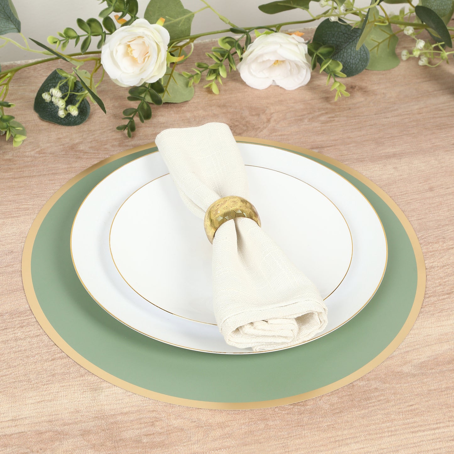 Sage green round disposable placemat with gold rim on a wooden table setting.