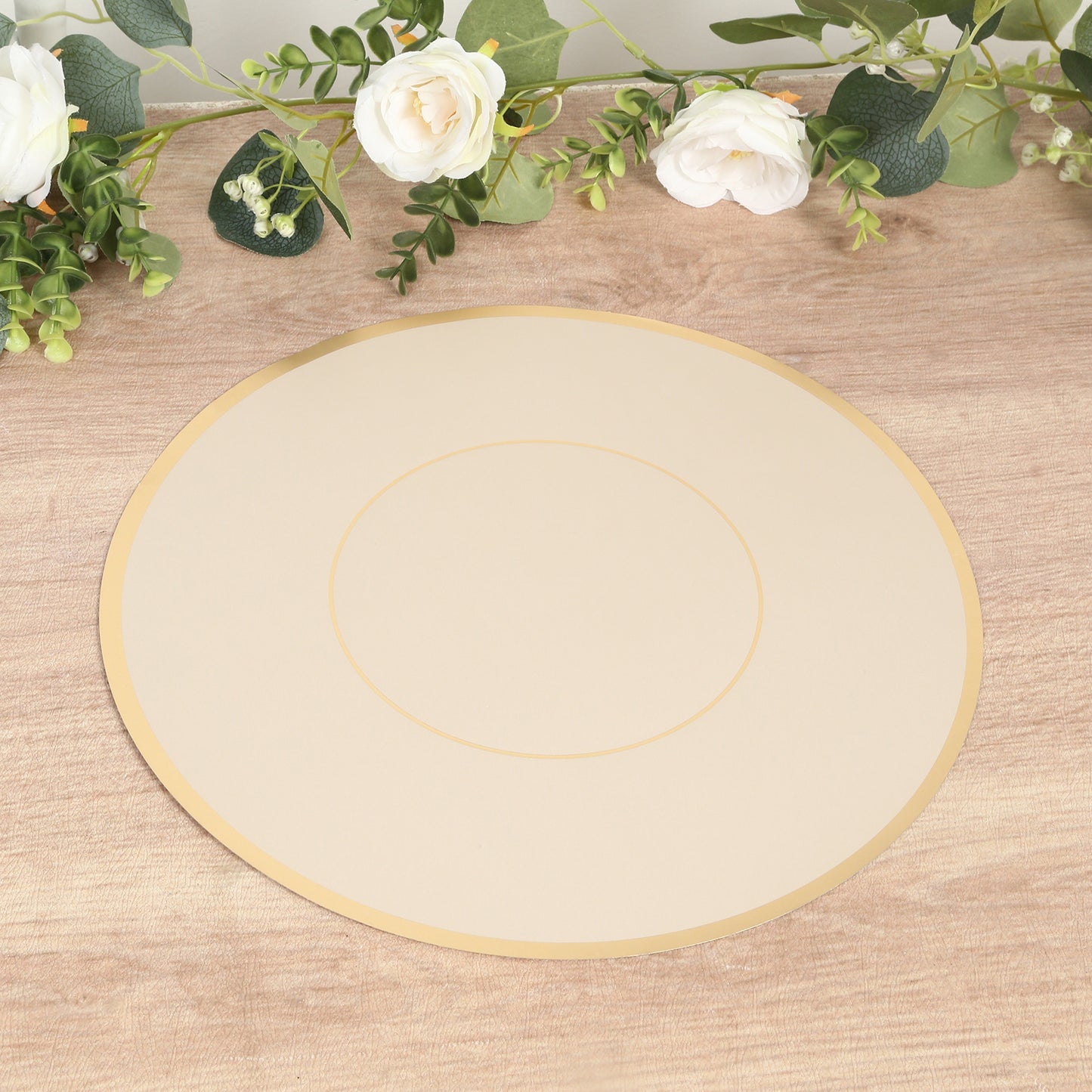 Taupe round disposable placemat with gold rim on a wooden table.