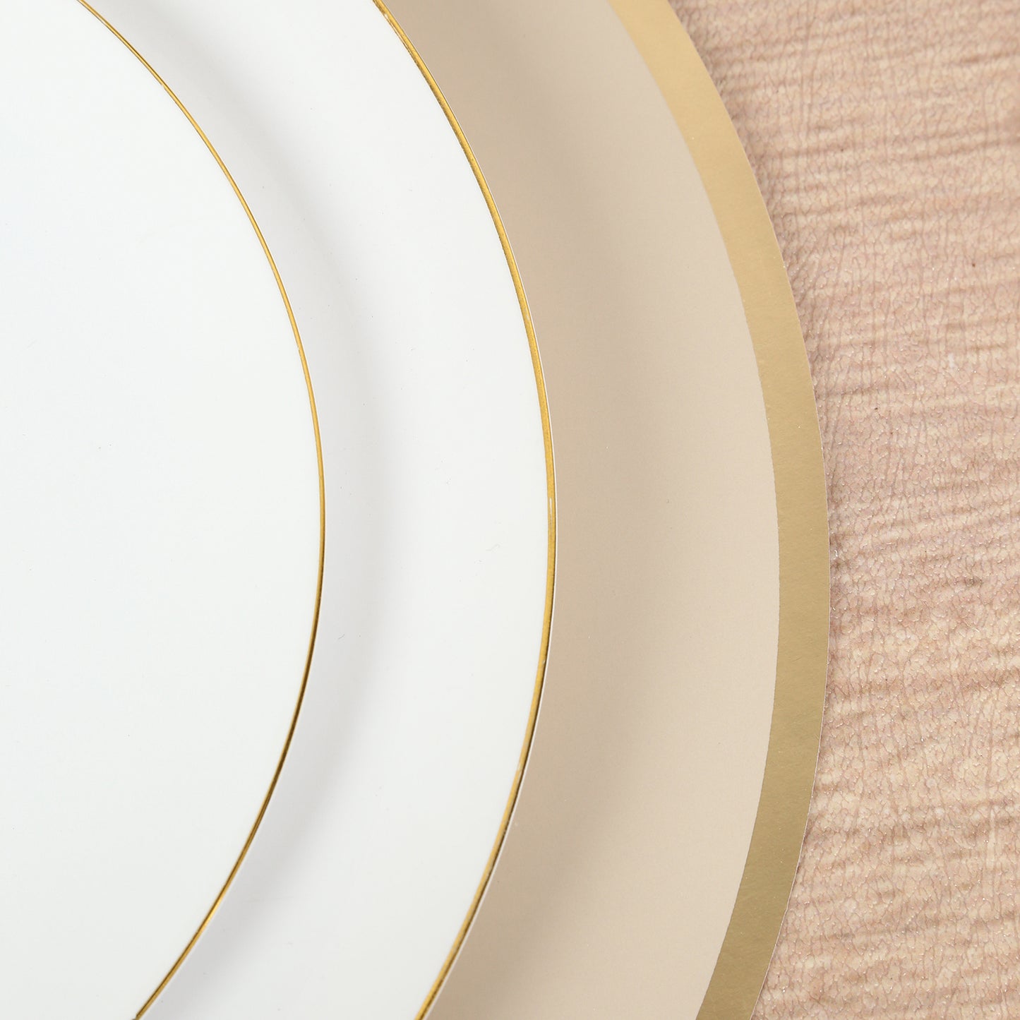Taupe round disposable table placemats with gold rim on a wooden surface.