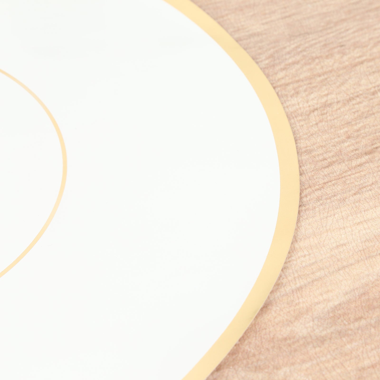 White round disposable table placemat with gold rim on a wooden surface.