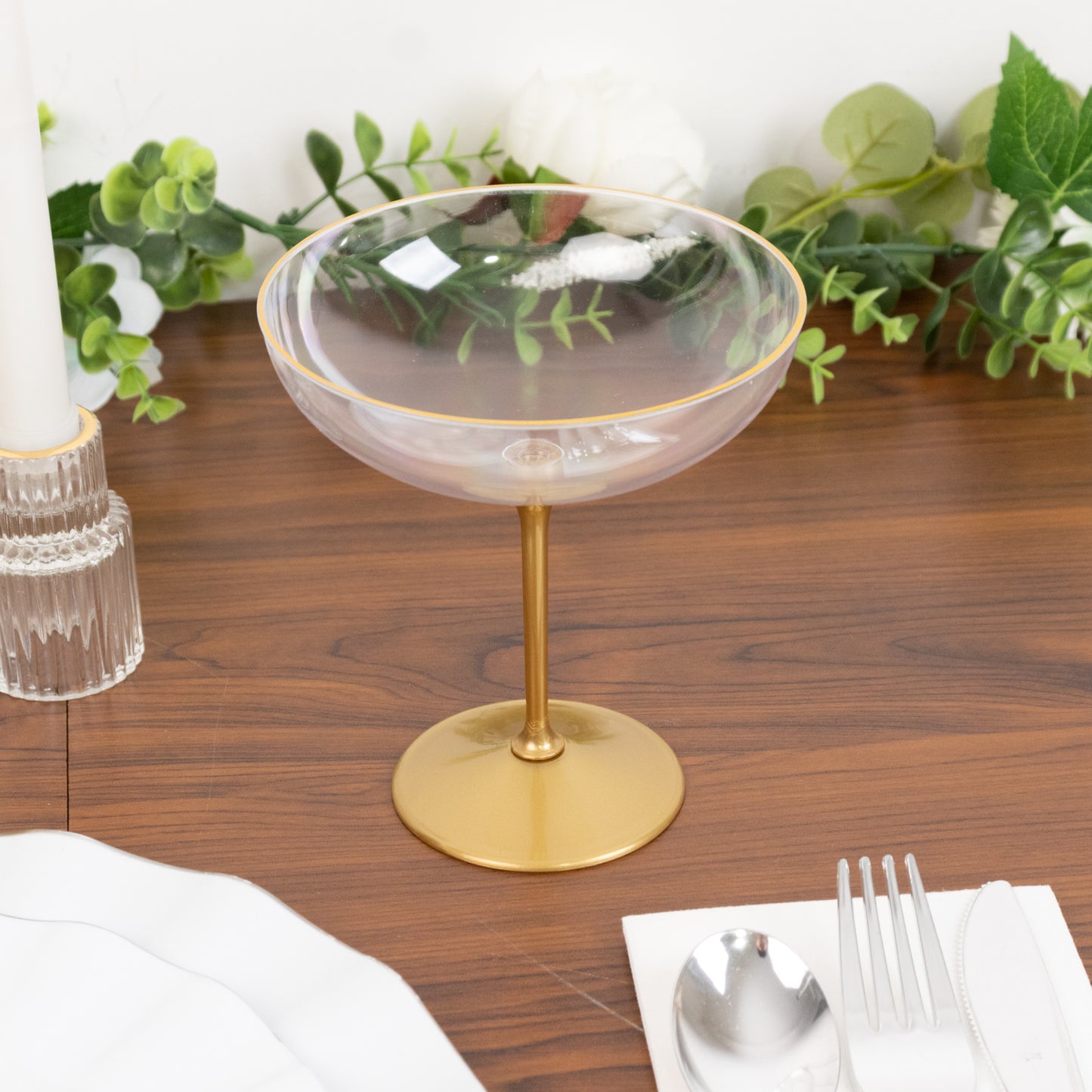 Clear glass dessert coupe with gold rim on wooden table