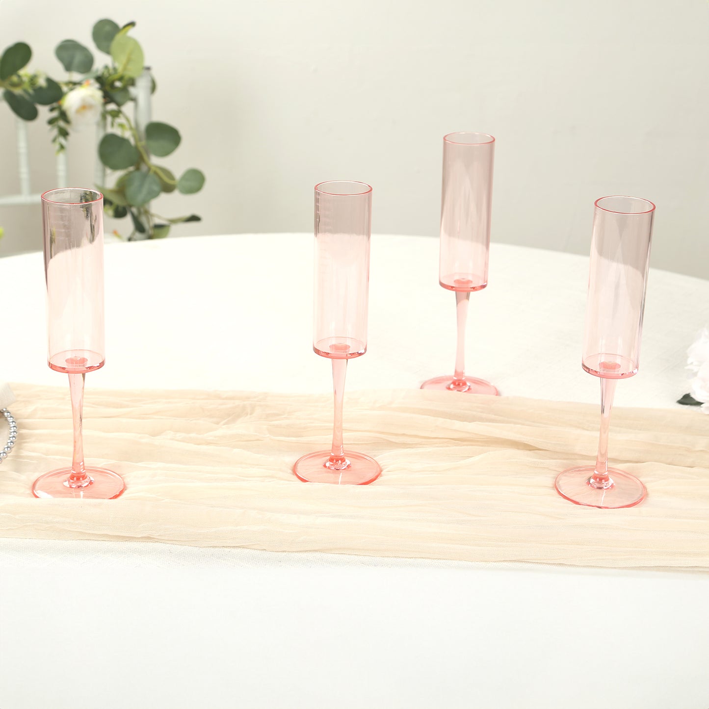 Transparent blush reusable plastic champagne flute glasses on a table.