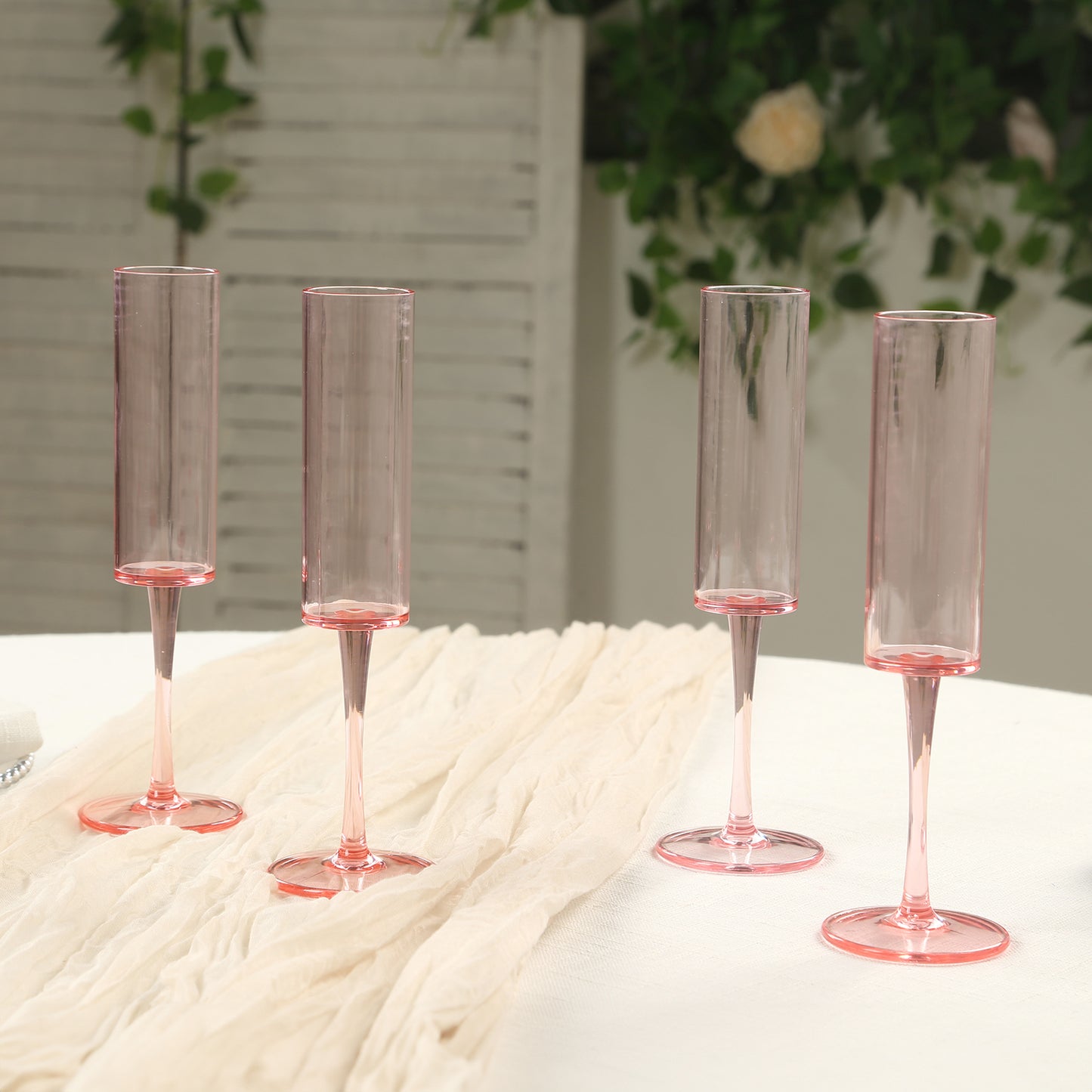 Transparent blush reusable plastic champagne flute glasses in cylindrical shape.