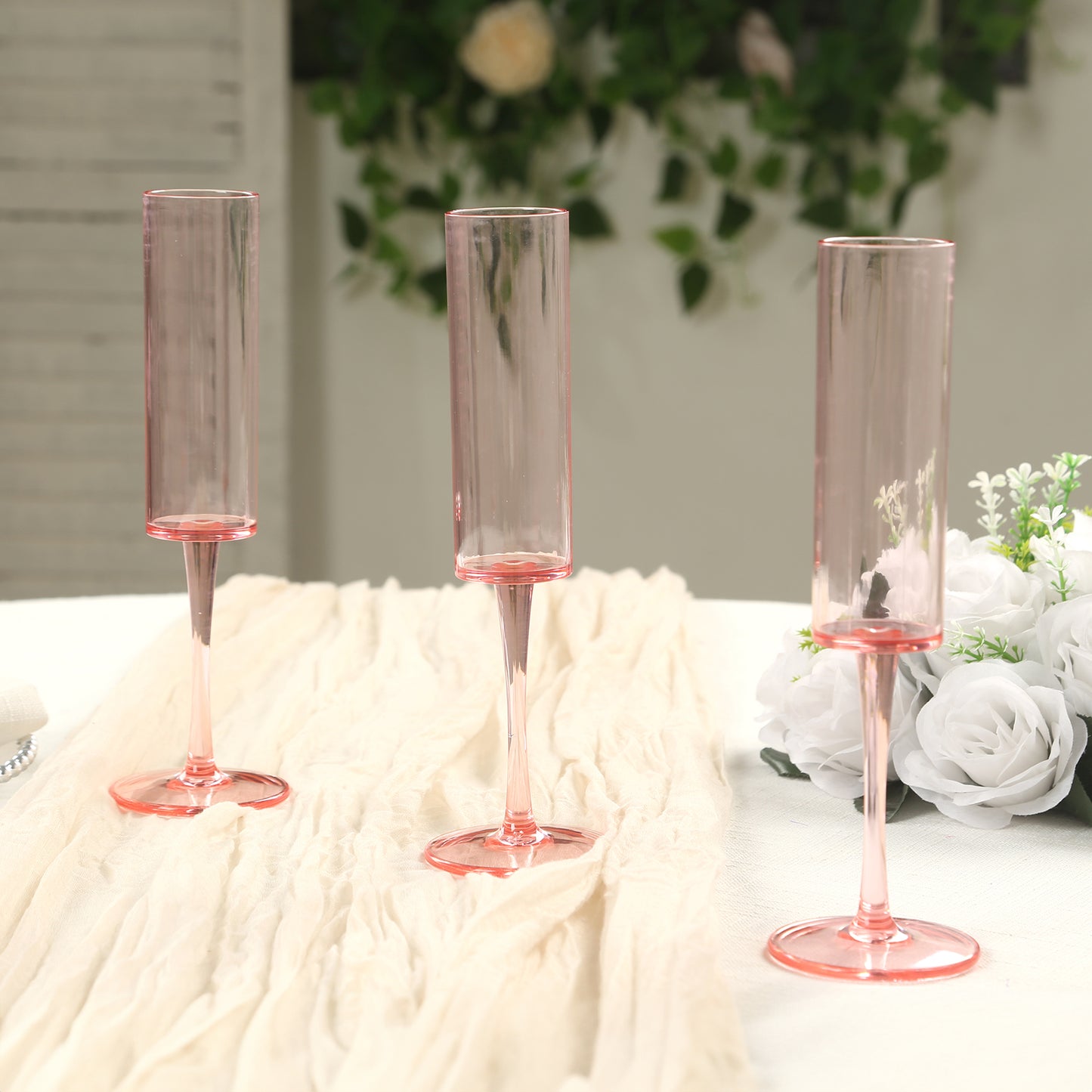 Transparent blush champagne flute glasses in cylindrical shape.