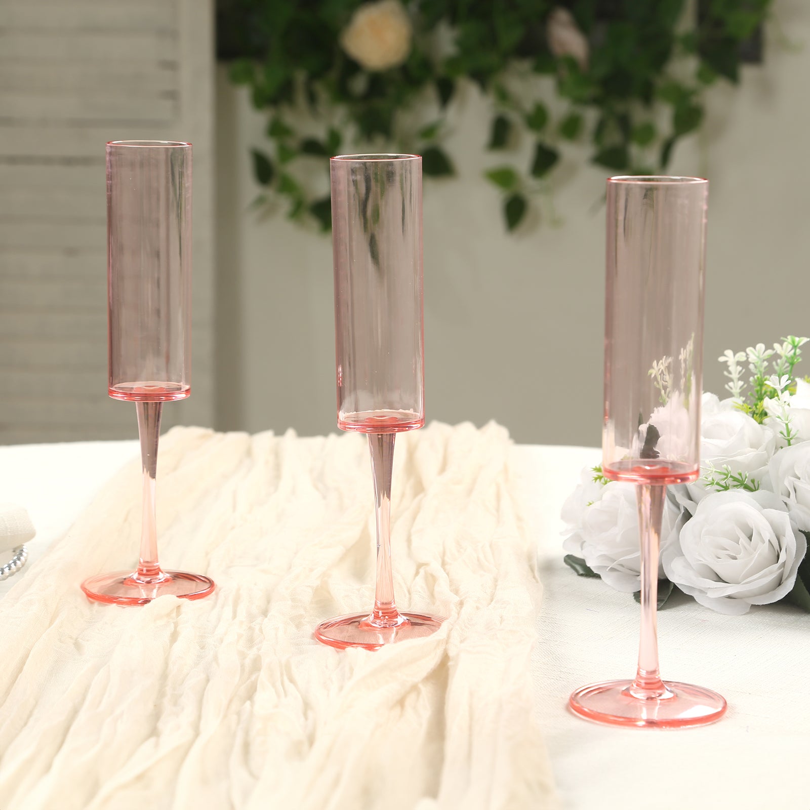 Transparent blush champagne flute glasses in cylindrical shape.