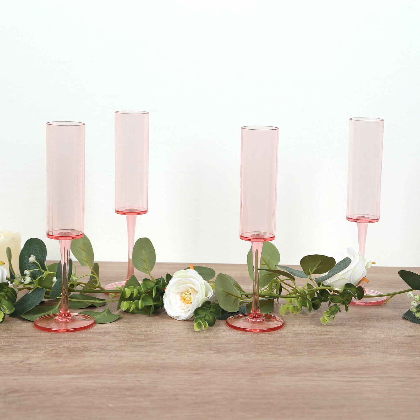 Transparent blush champagne flutes in cylindrical shape with long stems.