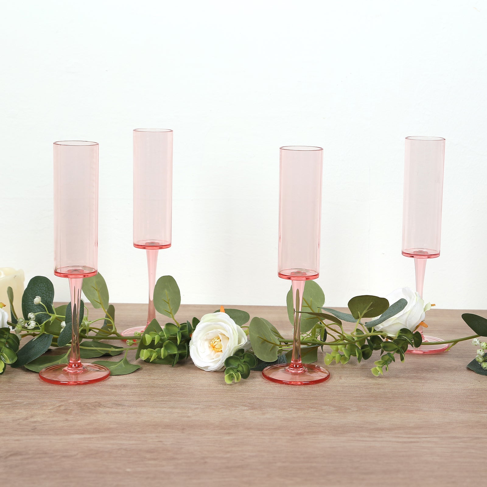 Transparent blush champagne flutes in cylindrical shape with long stems.