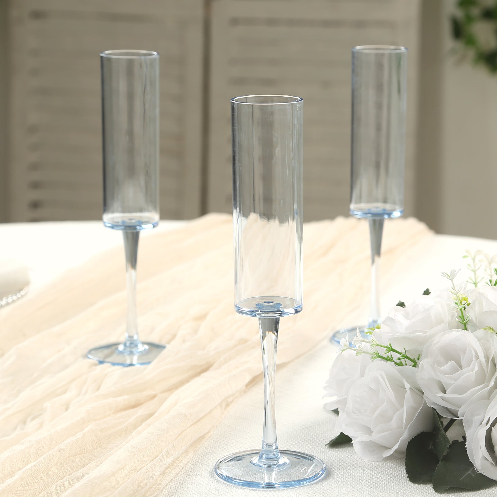 Transparent dusty blue reusable champagne flute glasses on a table.