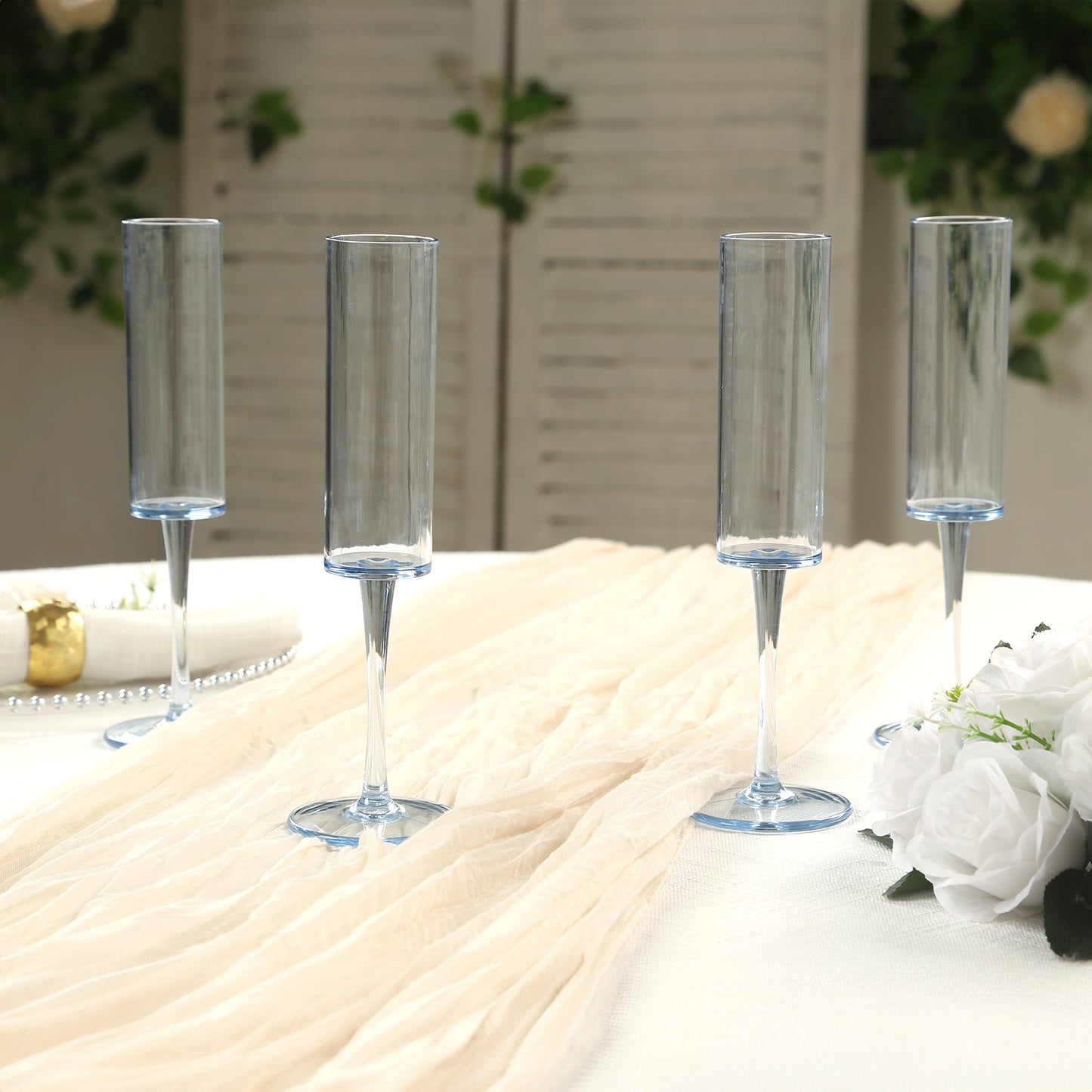 Transparent dusty blue reusable plastic champagne flutes on a table.