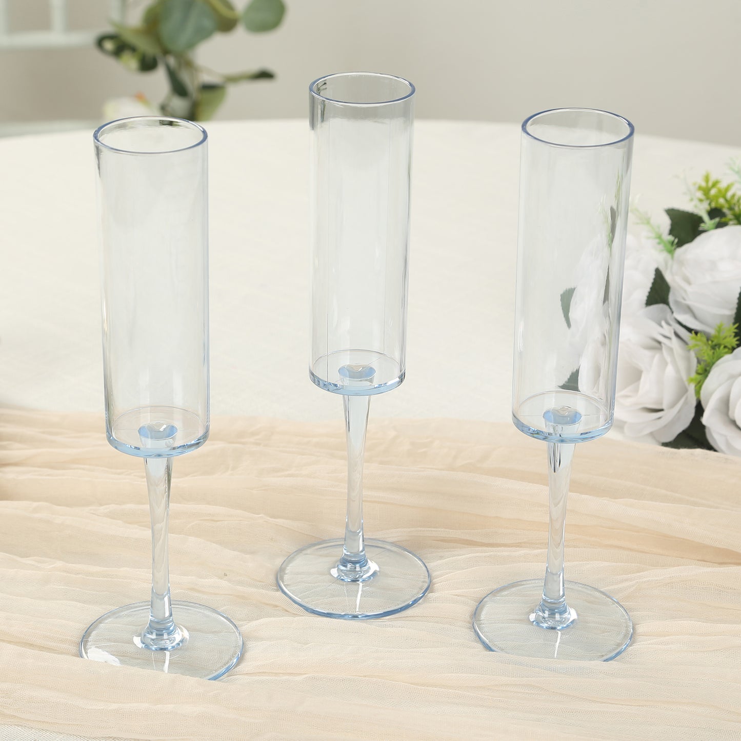 Transparent dusty blue champagne flutes with long stems on a light table setting.