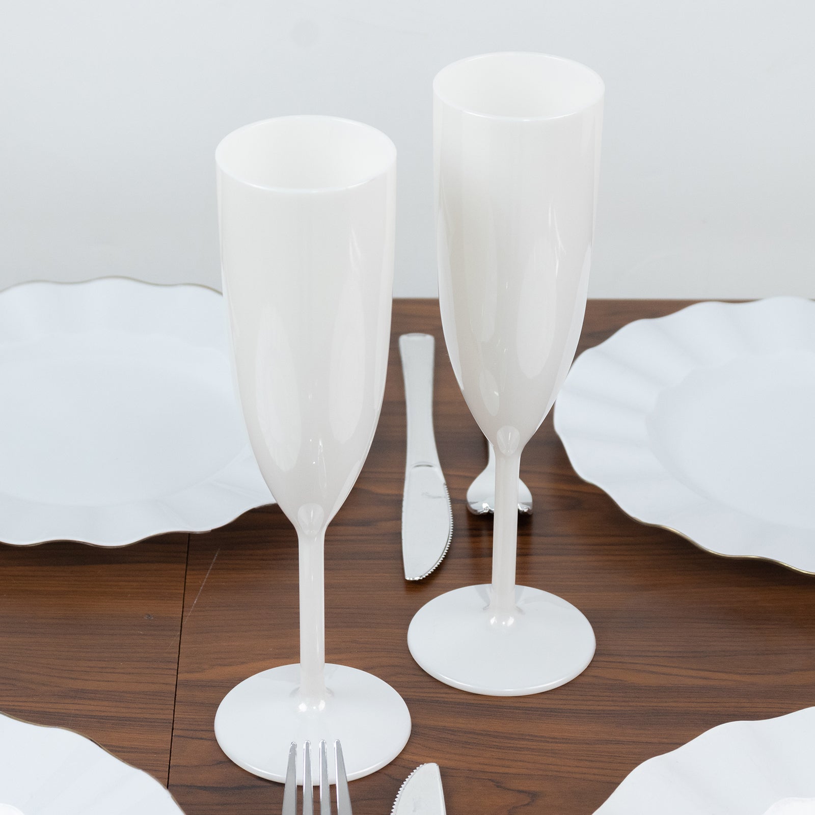 Pearl white shatterproof champagne flutes on a table setting.