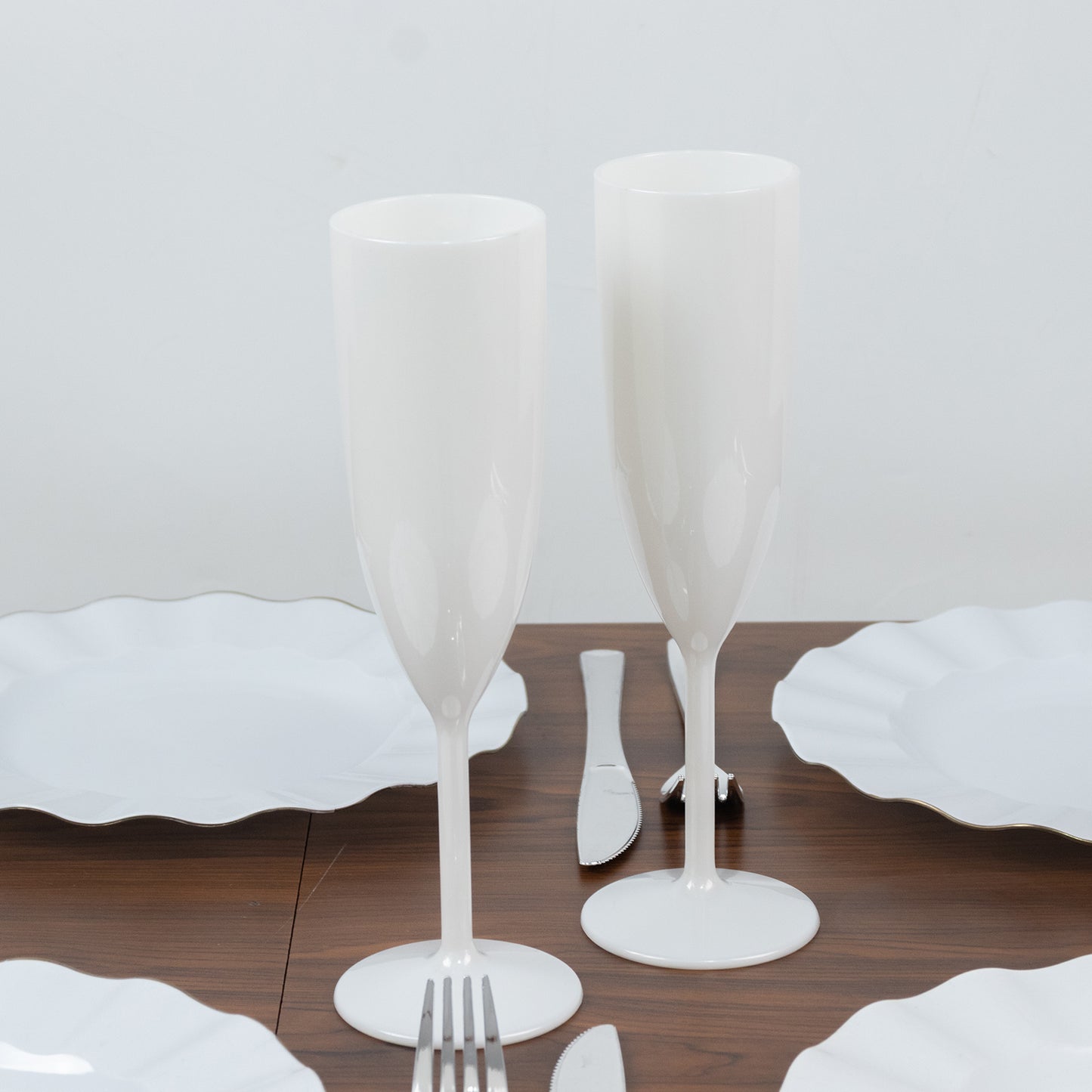 Pearl white shatterproof champagne flutes on a dining table.